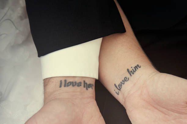 Hình xăm chữ "I love her" và "I love him" trên cổ tay, phong cách đơn giản, ảnh HD.