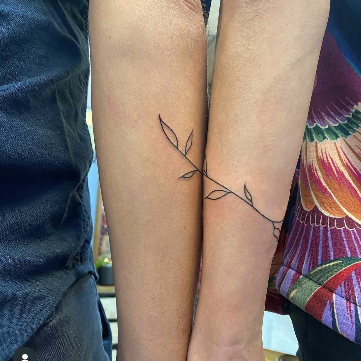 Hình xăm cành lá tối giản trên cánh tay, phong cách blackwork, ảnh độ phân giải cao.