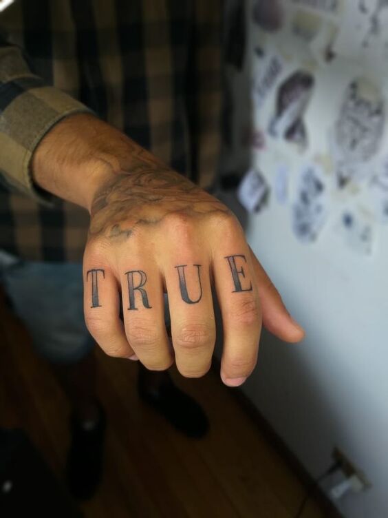 Hình xăm chữ "TRUE" trên ngón tay, phong cách blackwork, độ phân giải HD.