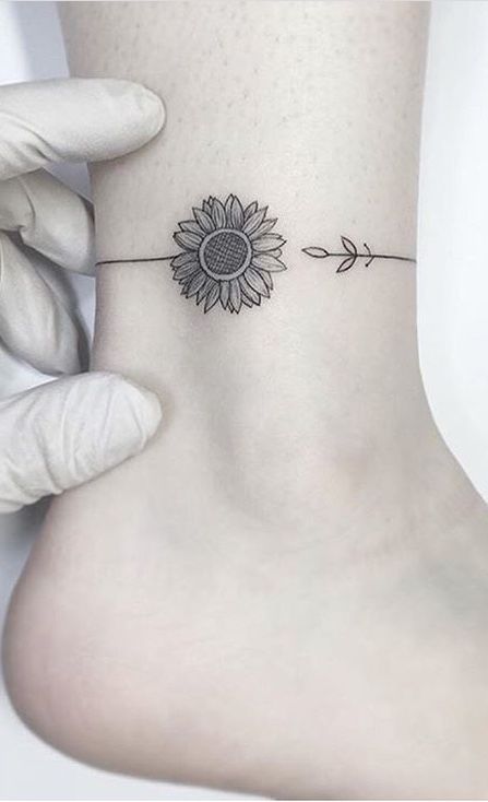 Hình xăm hoa hướng dương mini, phong cách blackwork trên mắt cá chân, chi tiết rõ nét, ảnh HD.