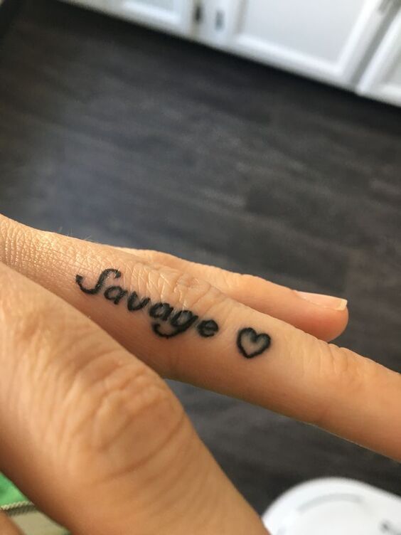 Hình xăm chữ "Savage" và trái tim trên ngón tay, phong cách đơn giản, ảnh độ phân giải HD.