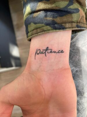 Hình xăm chữ "Patience" trên cổ tay, phong cách chữ viết tay, ảnh độ phân giải HD.