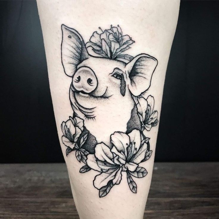 xăm heo mang lại tài lộc và thành công Hình xăm lợn và hoa trên bắp tay, phong cách blackwork, chi tiết rõ nét, ảnh độ phân giải HD.