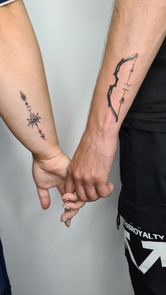 hình xăm mang ý nghĩa tình yêu Hình xăm cung tên và la bàn trên cánh tay, phong cách blackwork, chi tiết rõ nét, độ phân giải HD.