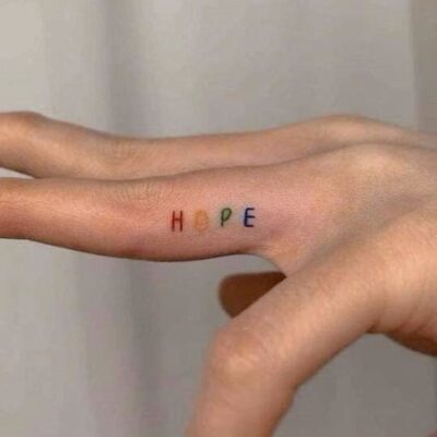 Hình xăm chữ "HOPE" nhỏ, nhiều màu trên ngón tay, phong cách tối giản, độ phân giải HD.