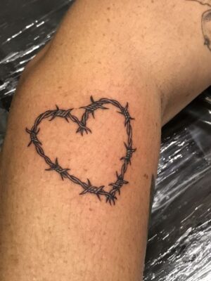 Hình xăm dây thép gai hình trái tim ở cánh tay, phong cách blackwork, chi tiết rõ nét, độ phân giải 400x300.