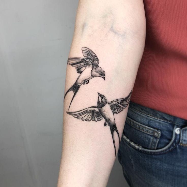 Hình xăm chim én trên cánh tay, phong cách blackwork chi tiết, ảnh chất lượng HD.