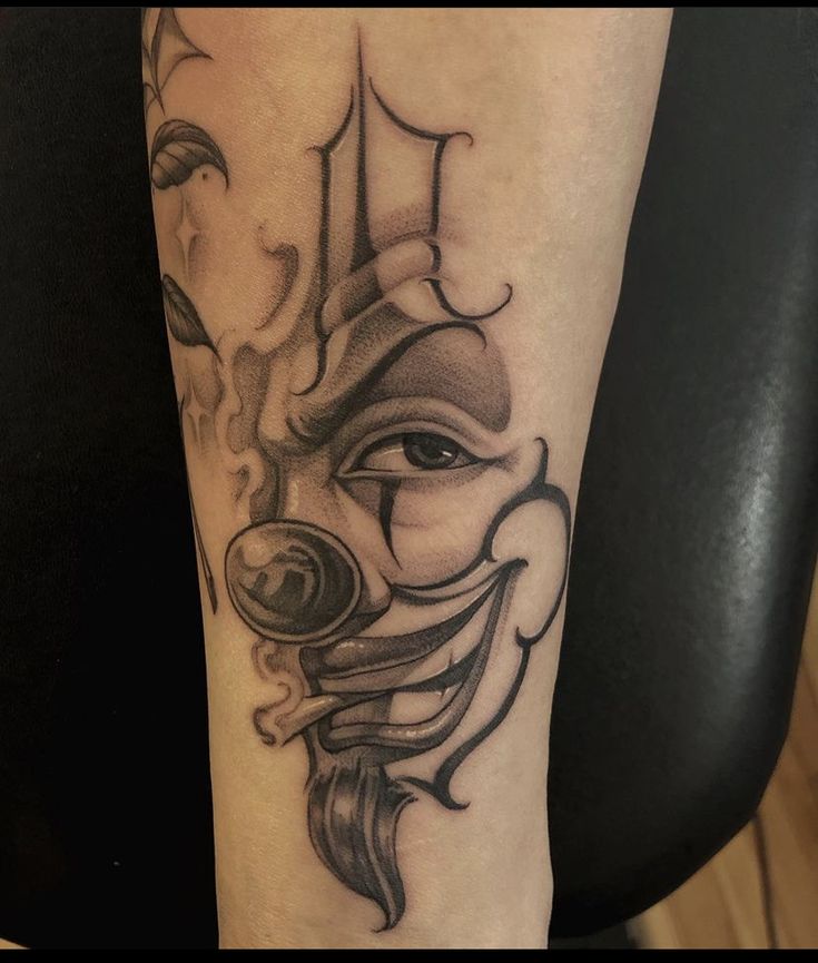 Hình xăm mặt hề phong cách blackwork trên cánh tay, chi tiết rõ nét, độ phân giải HD.