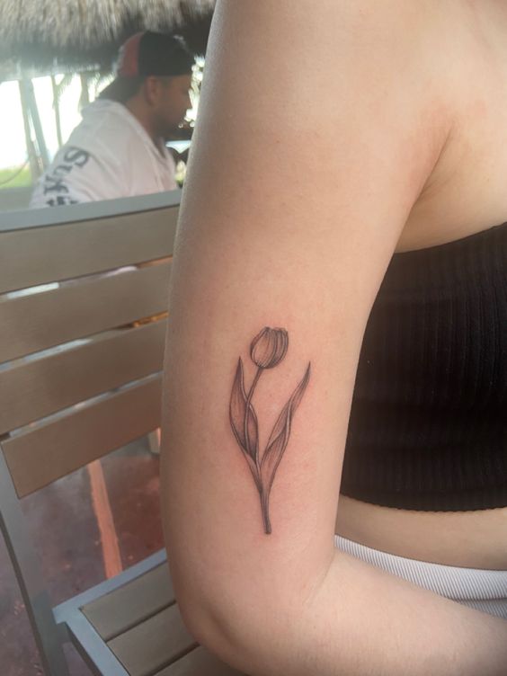 Hình xăm hoa tulip tối giản trên bắp tay, phong cách blackwork, chi tiết rõ nét, ảnh HD.