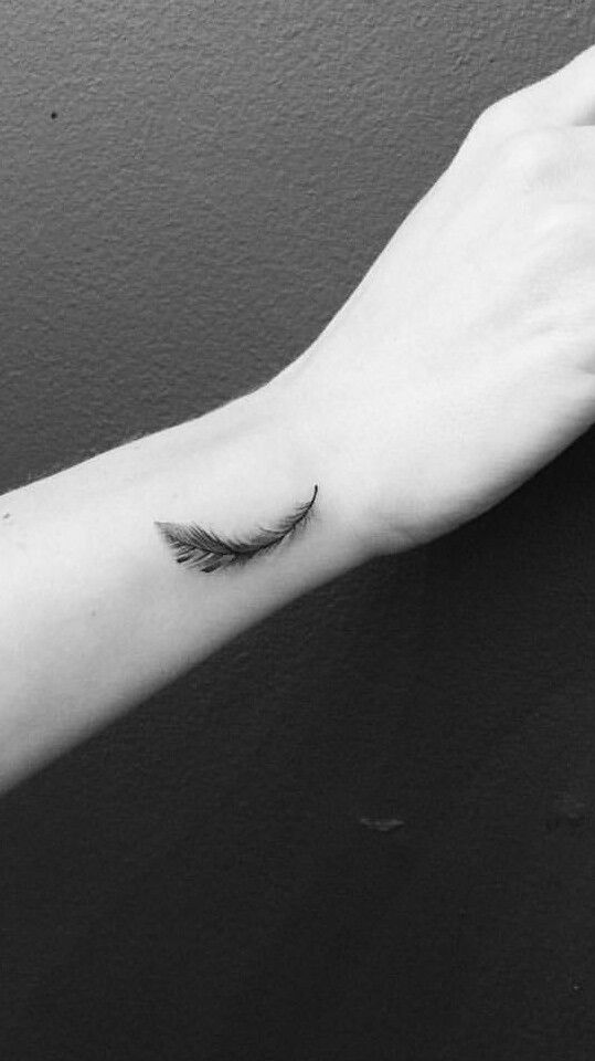 Hình xăm lông vũ mini trên cổ tay, phong cách blackwork, chi tiết rõ nét, ảnh độ phân giải cao.
