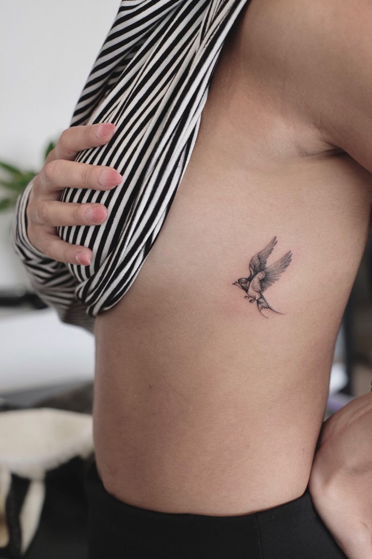 Hình xăm chim nhỏ trên sườn, phong cách blackwork, chi tiết rõ nét, độ phân giải HD.