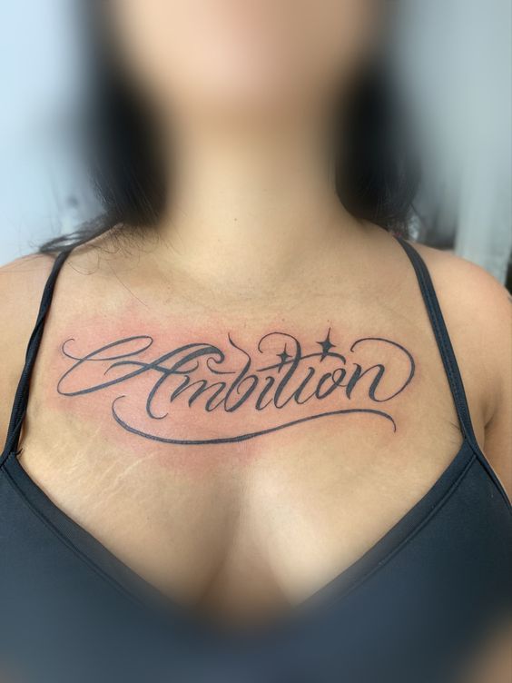 Hình xăm chữ "Ambition" trên ngực phong cách chữ viết tay, chi tiết rõ nét, ảnh HD.