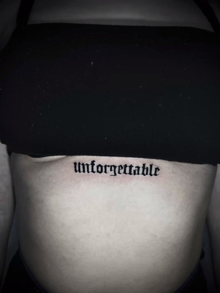 Hình xăm chữ "unforgettable" trên bụng, phong cách chữ đen, độ phân giải HD.