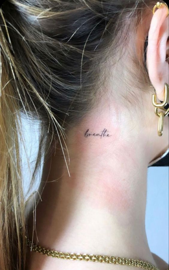 Hình xăm chữ "breathe" nhỏ ở sau gáy, phong cách tối giản, độ phân giải HD.