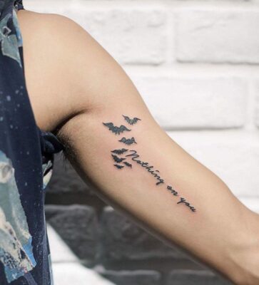 Hình xăm chữ và chim trên cánh tay, phong cách blackwork, chi tiết rõ nét, ảnh HD.