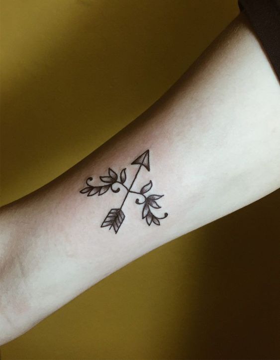 mẫu xăm cung tên đơn giản Hình xăm mũi tên và lá trên cánh tay, phong cách blackwork, chi tiết đơn giản, ảnh chất lượng HD.
