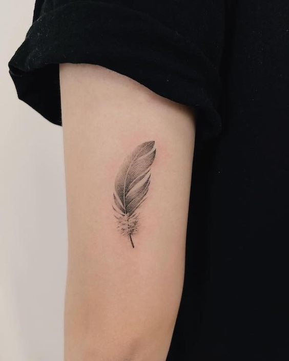Hình xăm lông vũ trên cánh tay, phong cách blackwork, chi tiết rõ nét, độ phân giải HD.