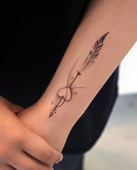 Hình xăm mũi tên và tim phong cách blackwork trên cánh tay, chi tiết tinh tế, ảnh HD.