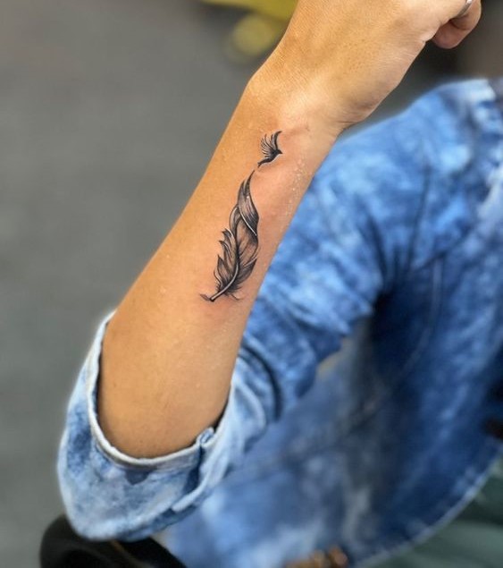 Hình xăm lông vũ trên cánh tay, phong cách blackwork, chi tiết tinh tế, ảnh HD.