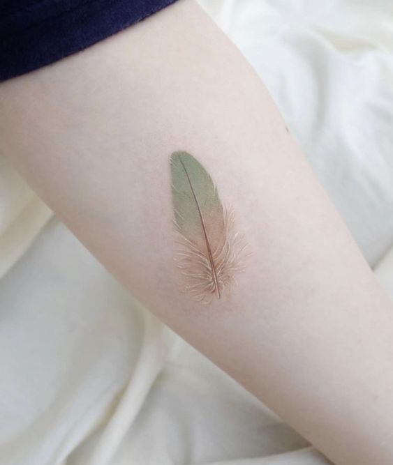 Hình xăm lông vũ mini trên tay, phong cách màu nước tinh tế, chi tiết rõ nét, độ phân giải HD.