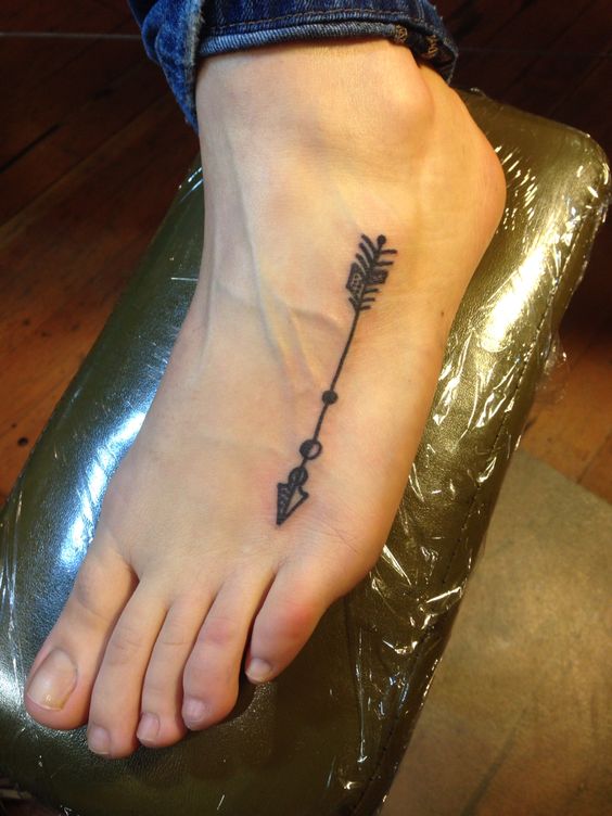 mẫu hình xăm mũi tên dưới bàn chân Hình xăm mũi tên blackwork trên mu bàn chân, phong cách tối giản, chi tiết rõ nét, ảnh HD.