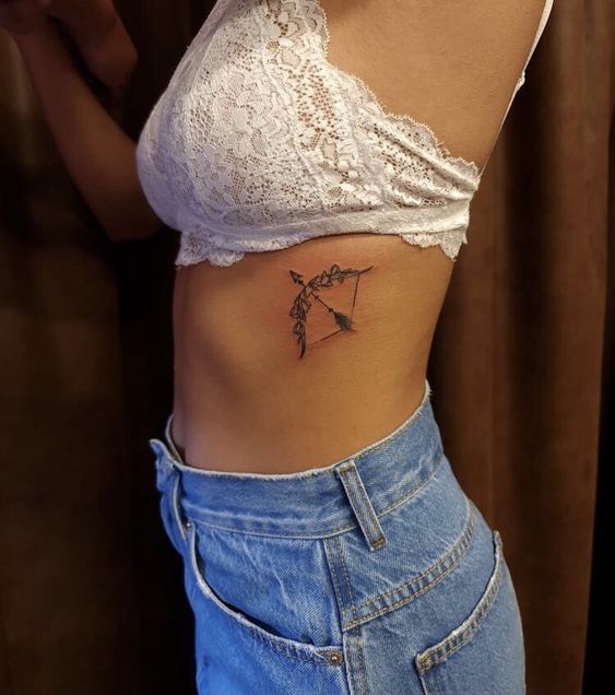 nghệ thuật xăm cung độc đáo dưới ngực Hình xăm cung tên mini ở eo, phong cách blackwork, ảnh chất lượng HD, chi tiết sắc nét.