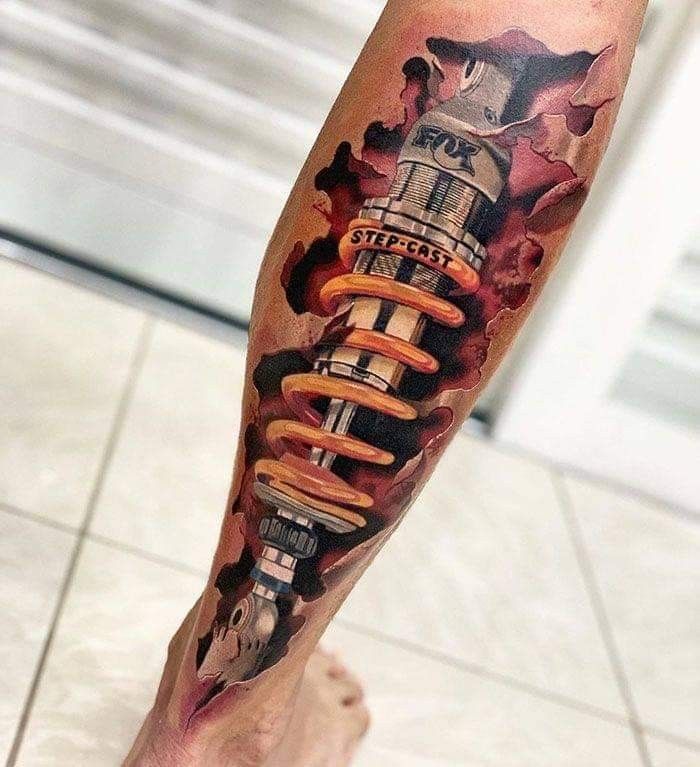 nghệ thuật tattoo phuộc ohlins trên chân Hình xăm 3D phuộc xe đạp trên bắp chân, phong cách hiện thực, chi tiết sắc nét, độ phân giải HD.