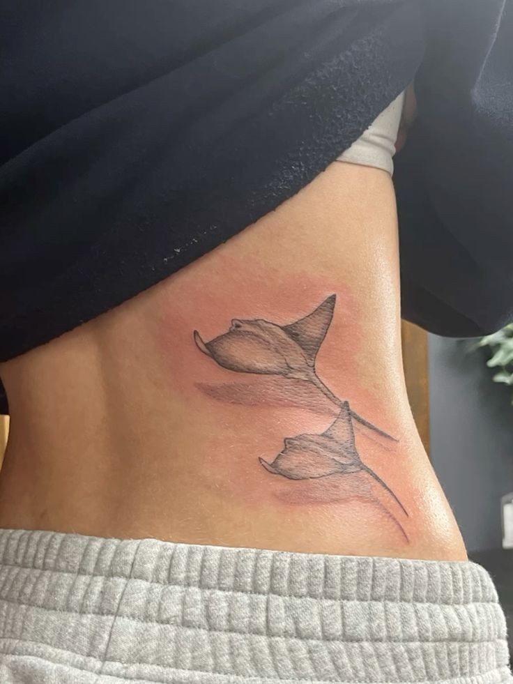 Hình xăm cá đuối mini trên lưng, phong cách blackwork, chi tiết rõ nét, độ phân giải cao.
