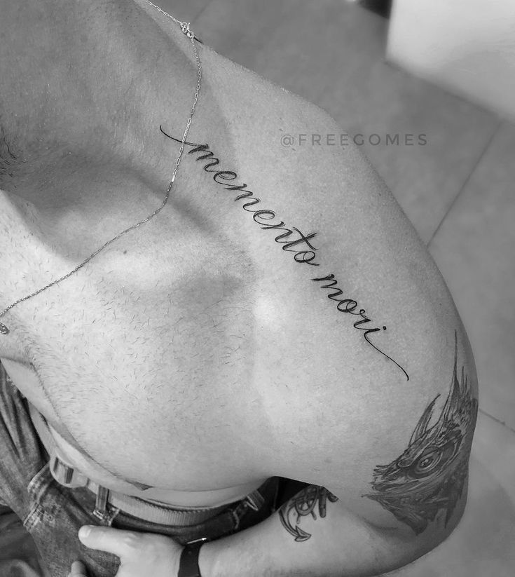tattoo chữ đầy ý nghĩa ở vai cho phái mạnh Hình xăm chữ "memento mori" trên vai, phong cách chữ viết tay, độ chi tiết cao, ảnh đen trắng rõ nét.