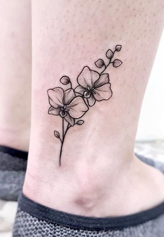 tattoo hoa lan nhỏ xinh trên cổ chân Hình xăm hoa lan trên mắt cá chân, phong cách blackwork tinh tế, ảnh HD rõ nét.