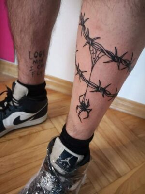 Hình xăm dây thép gai phong cách blackwork trên chân, chi tiết sắc nét, độ phân giải HD.