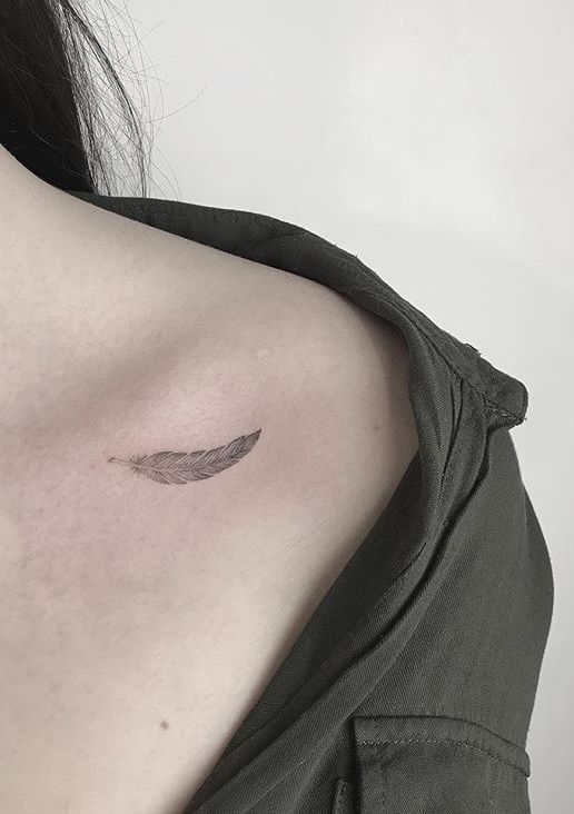 Hình xăm lông vũ mini trên vai, phong cách blackwork, ảnh độ phân giải cao.
