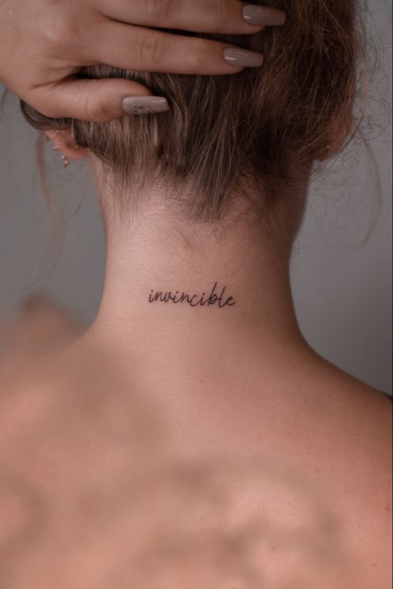 Hình xăm chữ "invincible" sau gáy, phong cách tối giản, ảnh độ phân giải cao, chi tiết rõ nét.