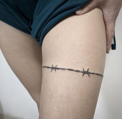 Hình xăm dây thép gai phong cách blackwork trên đùi, chi tiết rõ nét, ảnh HD.