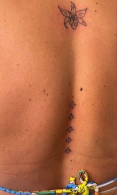 Hình xăm hoa mini ở lưng, phong cách blackwork, chi tiết tinh tế, độ phân giải HD.