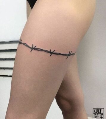 Hình xăm dây thép gai trên đùi, phong cách blackwork, chất lượng HD, chi tiết rõ nét.