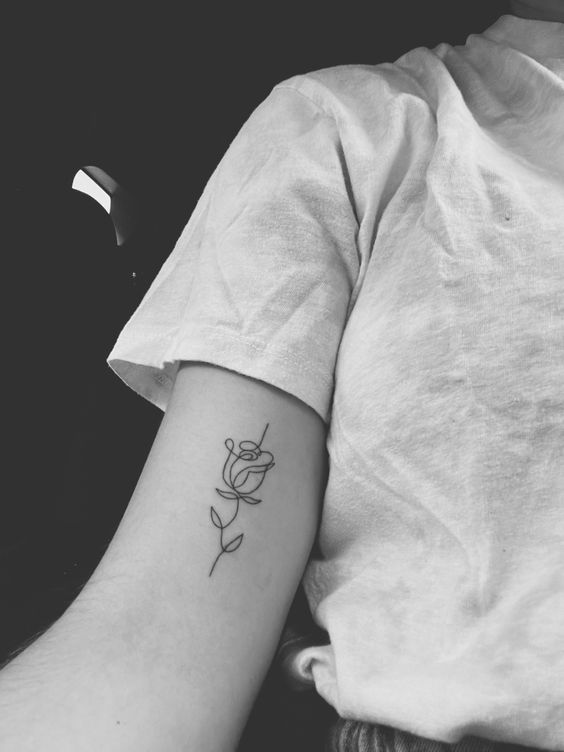 Hình xăm hoa hồng mini phong cách blackwork trên cánh tay, độ chi tiết cao, ảnh đen trắng rõ nét.