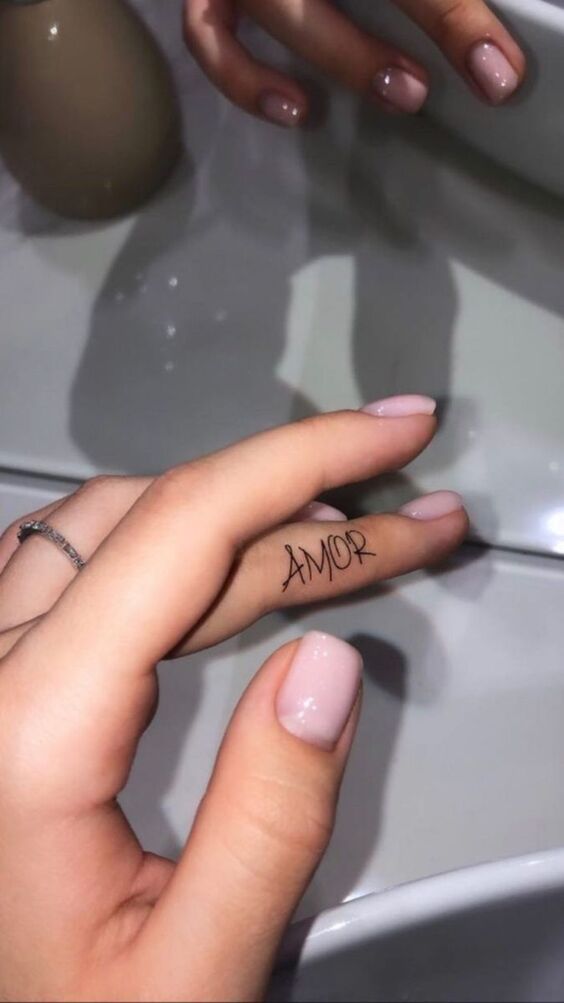 Hình xăm chữ "Amor" trên ngón tay, phong cách tối giản, ảnh HD, chi tiết rõ nét.