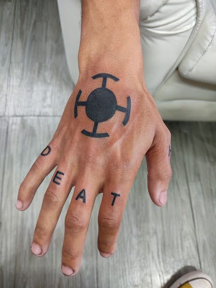 Hình xăm biểu tượng đen trên mu bàn tay, phong cách blackwork, chi tiết rõ nét, độ phân giải HD.