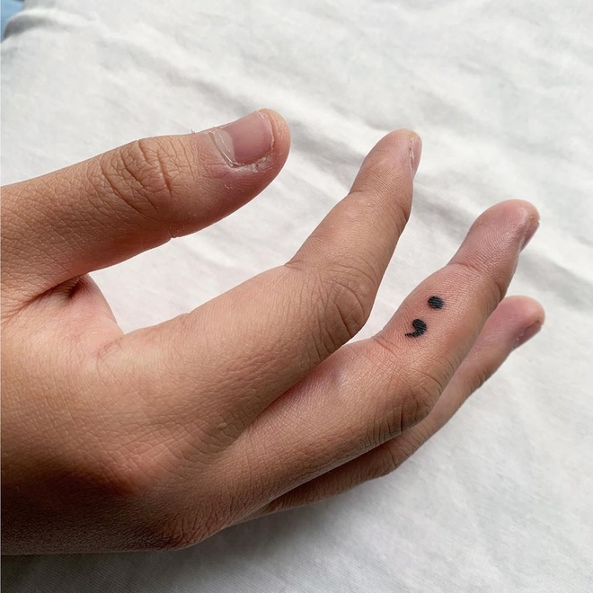 Hình xăm mini dấu chấm phẩy trên ngón tay, phong cách blackwork, ảnh HD chi tiết rõ nét.