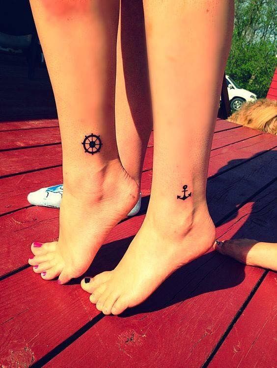 Hình xăm mỏ neo và bánh lái trên cổ chân, phong cách blackwork, chi tiết đơn giản. Ảnh HD.