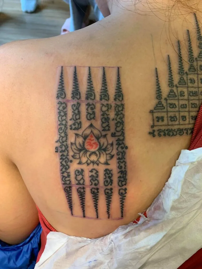Hình xăm hoa sen và chữ cổ trên vai theo phong cách blackwork, độ chi tiết cao, ảnh chất lượng HD.
