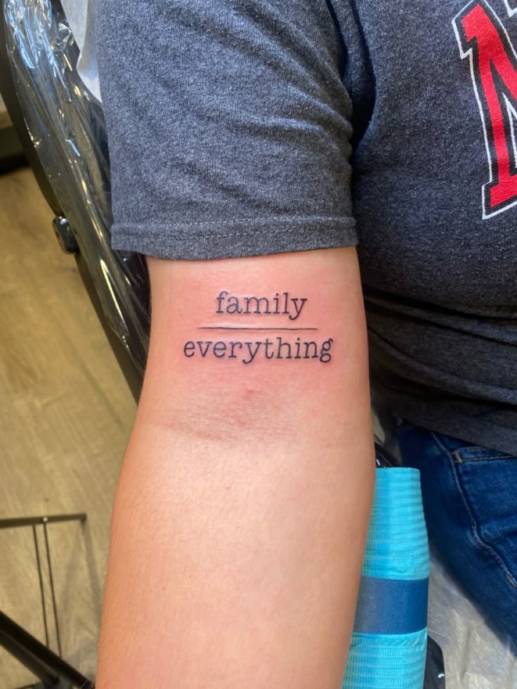 Hình xăm chữ "family over everything" trên cánh tay, phong cách tối giản, độ phân giải HD.