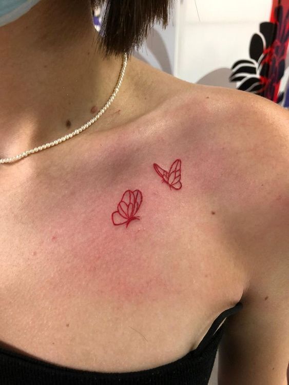 Hình xăm bướm mini phong cách linework ở xương quai xanh, màu đỏ, độ phân giải HD.
