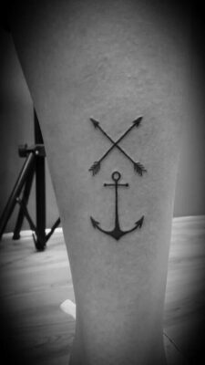 Hình xăm mỏ neo và mũi tên trên chân, phong cách blackwork, chi tiết rõ nét, độ phân giải HD.