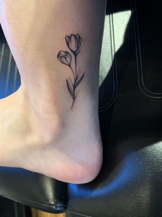 Hình xăm hoa tulip mini ở mắt cá chân, phong cách blackwork, chi tiết rõ nét, độ phân giải HD.