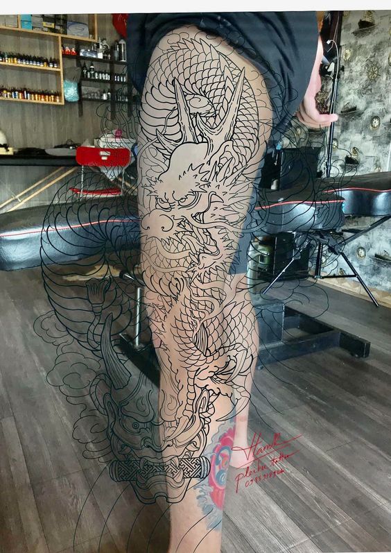Hình xăm rồng chi tiết, phong cách blackwork, trên chân, độ phân giải HD, không gian tiệm xăm.