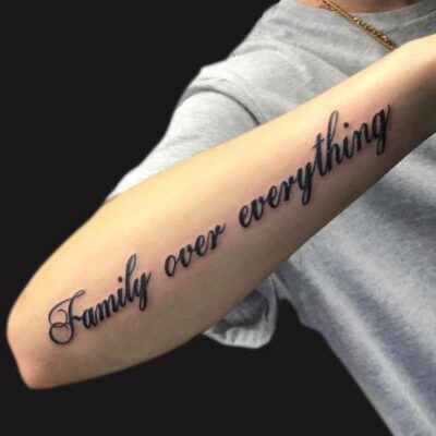 Hình xăm chữ "Family over everything" trên cánh tay, phong cách cổ điển, chi tiết rõ nét, độ phân giải HD.