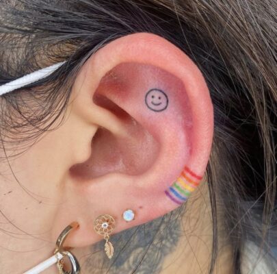 Hình xăm mini mặt cười và cầu vồng trên tai, phong cách tối giản, ảnh chất lượng HD.