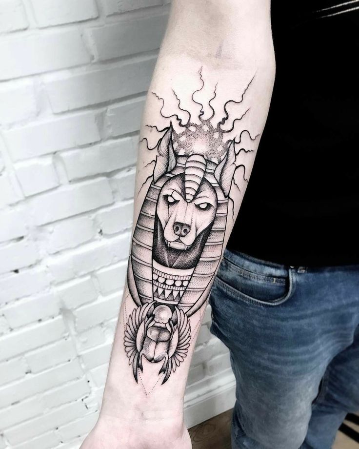 Hình xăm Anubis trên cánh tay, phong cách blackwork, chi tiết rõ nét, độ phân giải HD.